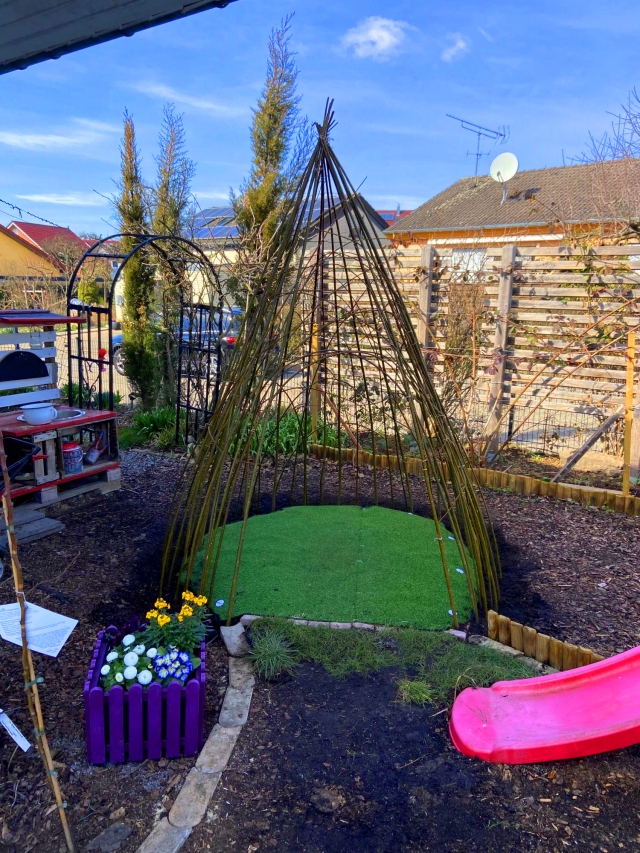 Weidentipi aus Weidenruten, die Weidenruten sind oben mit Strick gebunden, im Tipi ist ein Flies