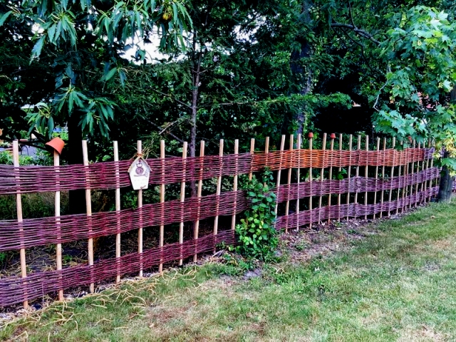 langer Weidenzaun auf einer Wiese mit 3 gleichbreiten waagerechten Flechtabschnitten