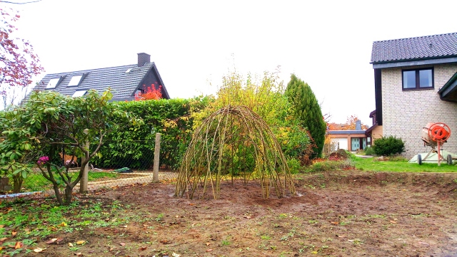 Weideniglu neu angelegt auf lehmigen Boden, rechts ein Einfamilienhaus